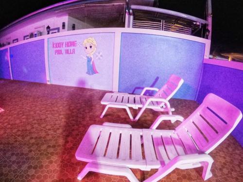 three chairs and a bench in front of a stage at Green house Pool Villa in Cha Am