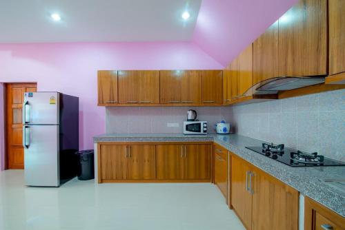a kitchen with wooden cabinets and a white refrigerator at Green house Pool Villa in Cha Am