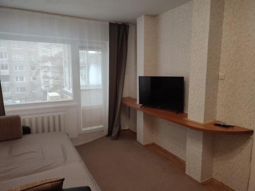 a living room with a tv on a shelf next to a window at ShortStopPasilaiciai in Vilnius