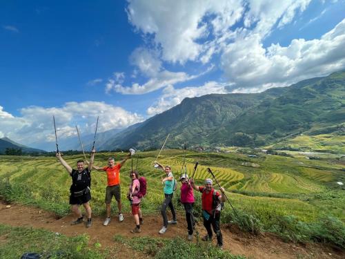 Eine Gruppe von Menschen, die auf einem Hügel mit den Händen in der Luft stehen in der Unterkunft SaPa Big Tree Hmong Homestay in Sa Pa