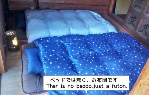 Una cama con un edredón azul con escritura. en Rino to Hiroto no Himitsukichi - Vacation STAY 92317v, en Minamiizu