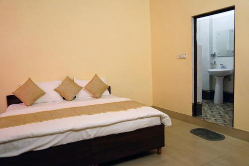 1 dormitorio con cama con almohadas y lavamanos en Atithi Hotel en Paliā Kalān