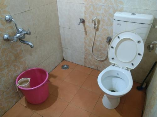 a bathroom with a toilet and a pink bucket at Samz estate stay 2BHK in Madikeri