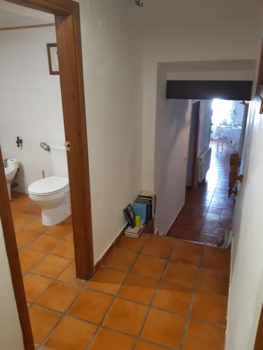 a bathroom with a toilet and a hallway at Musas Gastro Casa Rural in Valdealgorfa