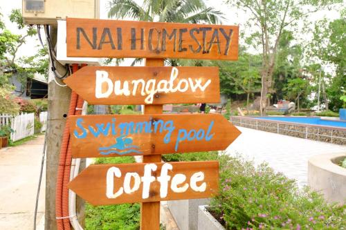 a wooden sign with several signs on a pole at NAI Homestay in Ben Tre