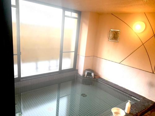 baño con suelo de baldosa y ventana en おばな旅館 富貴亭, 