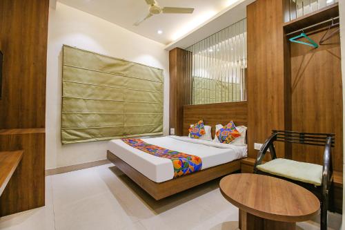 a bedroom with a bed and a table and a chair at FabHotel Royal Palace II in Bhopal