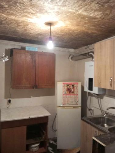 a kitchen with a white refrigerator and wooden cabinets at ონის რაიონი სოფელი ზუდალი in Nigvznara