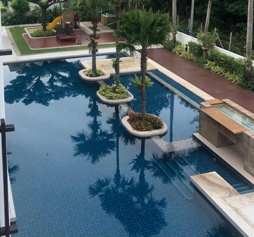 a swimming pool with palm trees reflecting in the water at Vimanlay A302 - Happiness Elevated in Ban Bo Talung