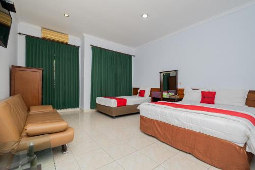 a bedroom with two beds and a couch and a tv at RedDoorz near Bojonegoro Train Station in Bojonegoro