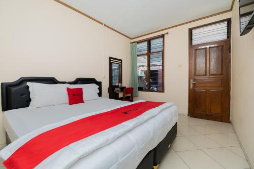 a bedroom with a large bed with a red blanket at RedDoorz near Bojonegoro Train Station in Bojonegoro
