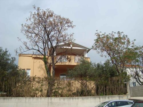 a house behind a fence with a tree at Apartment in Zadar/Zadar Riviera 7837 in Smirić