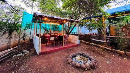 una casa con mesa, sillas y chimenea en SPM Residency, From Live2Travel Group. en Masinagudi