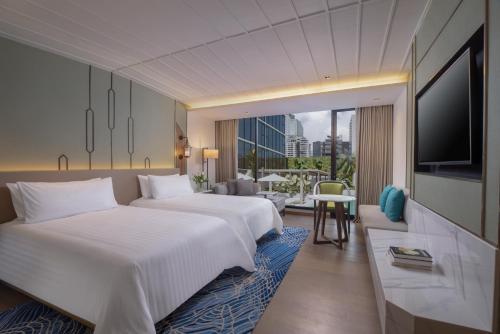 a hotel room with two beds and a television at Nysa Hotel Bangkok Sukhumvit 11 in Bangkok