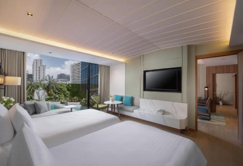 a hotel room with two beds and a flat screen tv at Nysa Hotel Bangkok Sukhumvit 11 in Bangkok