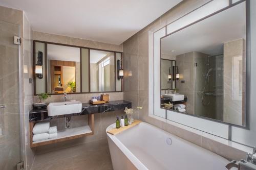 a bathroom with a tub and a sink and a mirror at Nysa Hotel Bangkok Sukhumvit 11 in Bangkok