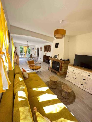 ein Wohnzimmer mit einem gelben Sofa und einem TV in der Unterkunft Maison Climatisée in Saint-Hippolyte