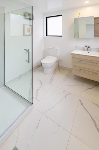 a bathroom with a toilet and a glass shower at New Brighton Beach Explore - King Bed and sofa bed in Christchurch