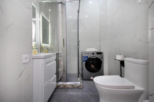 a bathroom with a toilet and a washing machine at Апартаменты бизнес-класса в ЖК Amir in Almaty