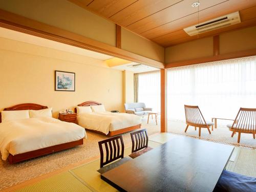 1 Schlafzimmer mit 2 Betten, einem Tisch und Stühlen in der Unterkunft Auberge de South Terrace in Shirahama