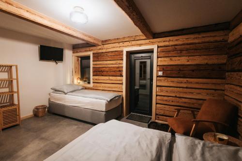 a bedroom with two beds and a wall of wood at Nasza Chata in Duszniki Zdrój