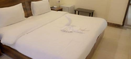 a large white bed with white sheets and pillows at The Orchid Inn in Gurgaon