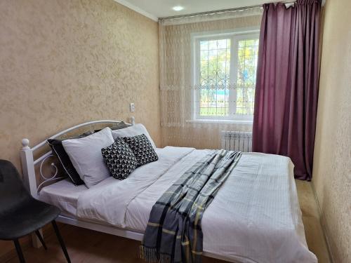 a bedroom with a bed with pillows and a window at Аппартаменты 2 / х комнатная in Ustʼ-Kamenogorsk