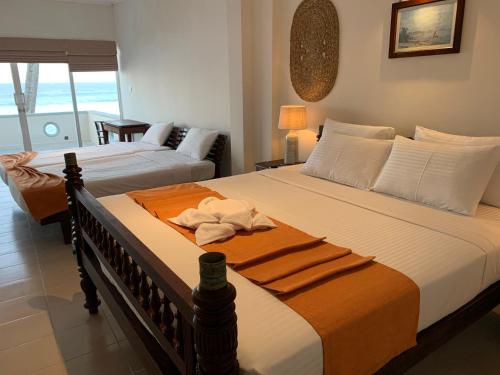 a bedroom with two beds with towels on it at Neevana Hotel Hikkaduwa in Hikkaduwa