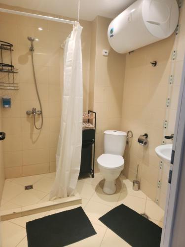 a bathroom with a shower and a toilet and a sink at Grand Midia Resort, Sky level apartments in Aheloy