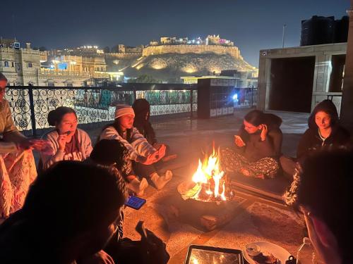 a group of people sitting around a fire at Hostel Go And Stay Jaisalmer in Jaisalmer