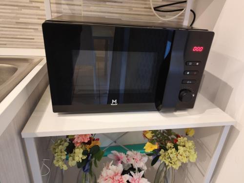 a microwave oven sitting on a shelf with flowers at Appartamento c&y Monte san Gabriele in Novara