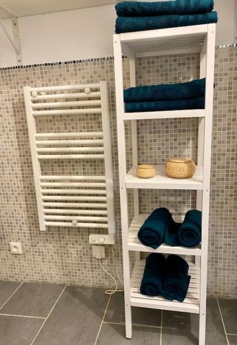 - deux étagères blanches dans une salle de bains pourvue de serviettes bleues dans l'établissement Joli duplex neuf centre Seclin., à Seclin