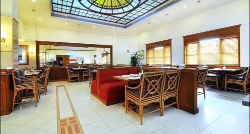 a restaurant with a red couch and tables and chairs at Abad Atrium in Cochin