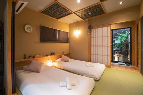 two beds in a room with a window at Konayuki Inn Machiya 粉雪の宿 6min walk from Kyoto St in Kyoto