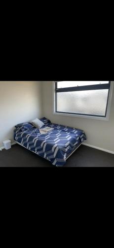 a bed in a room next to a window at Cosy Room with lock and work area in Truganina
