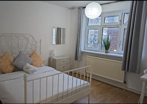 a white bedroom with a bed and a window at London E1 Rooms in London