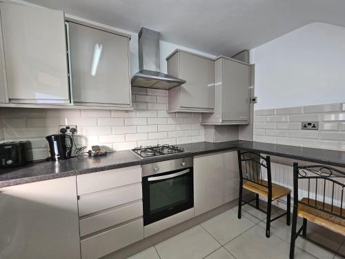 a kitchen with white cabinets and a stove top oven at London E1 Rooms in London