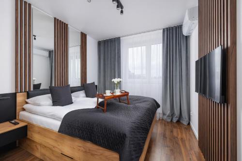 a bedroom with a bed with a table and a tv at Near EXPO Cracow Elegant Apartment by Renters in Krakow