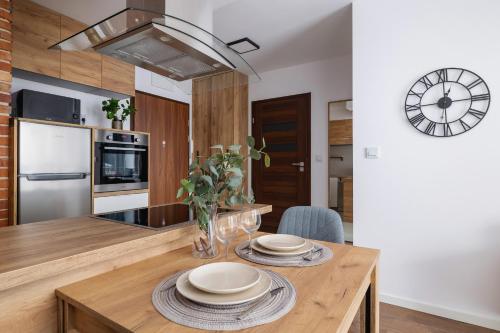 a kitchen with a wooden table with plates on it at Near EXPO Cracow Elegant Apartment by Renters in Krakow