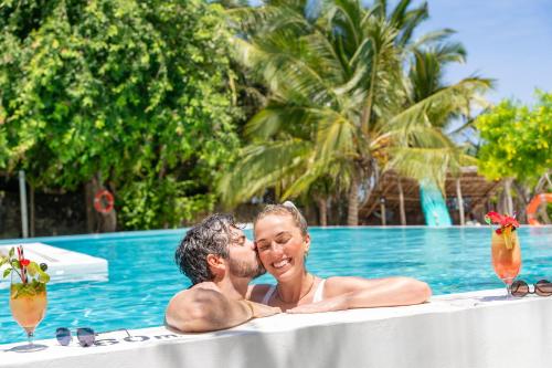a man and a woman sitting in a swimming pool at Alma Boutique Hotel in Jambiani