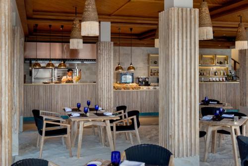 a dining room with tables and chairs and a kitchen at Emerald Faarufushi Resort & Spa - Deluxe All Inclusive in Raa Atoll