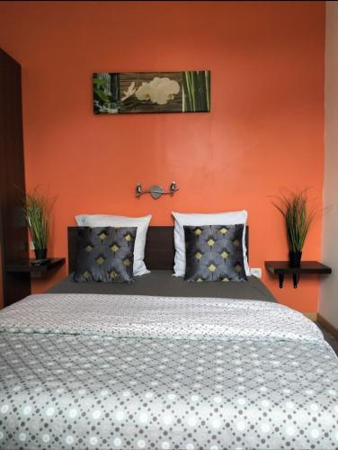 - une chambre dotée d'un lit avec un mur orange dans l'établissement Le Domaine, à Moustey