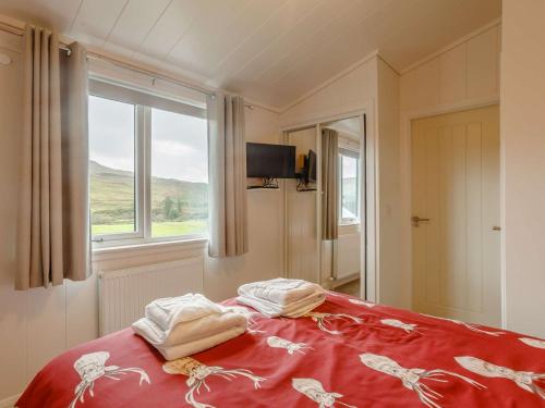 a bedroom with a bed with a red blanket and a window at 2 Bed in Portree 87578 in Portree