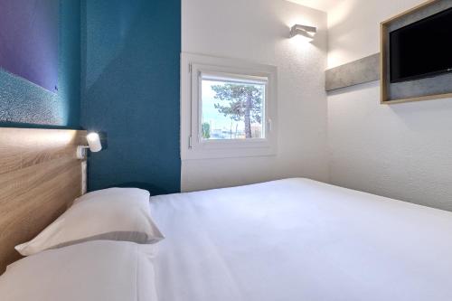 a bedroom with a white bed and a window at Kyriad Direct Moulins Sud - Yzeure in Moulins