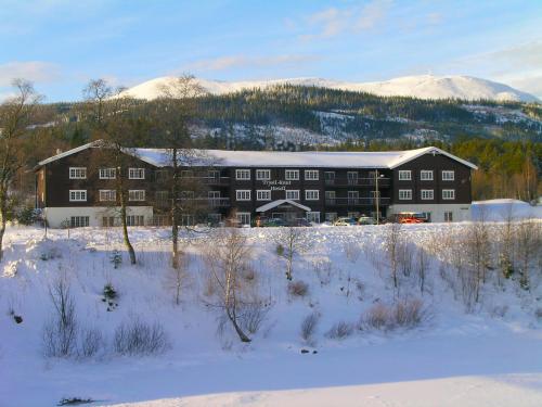 a large building in the snow with a mountain in the background at Trysil-Knut Hotel in Trysil