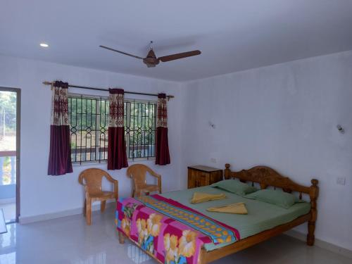 a bedroom with a bed with two chairs and a window at Gabriel & Felicidade Villa in Mandrem