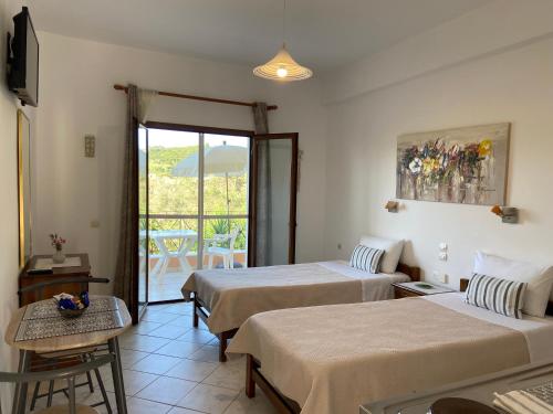 um quarto de hotel com duas camas e uma varanda em Floros Apartments em Agios Stefanos