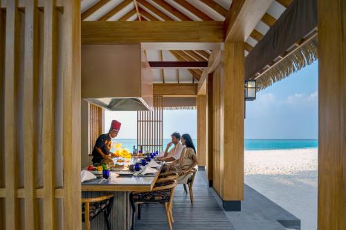 a group of people sitting at a table on the beach at Emerald Faarufushi Resort & Spa - Deluxe All Inclusive in Raa Atoll