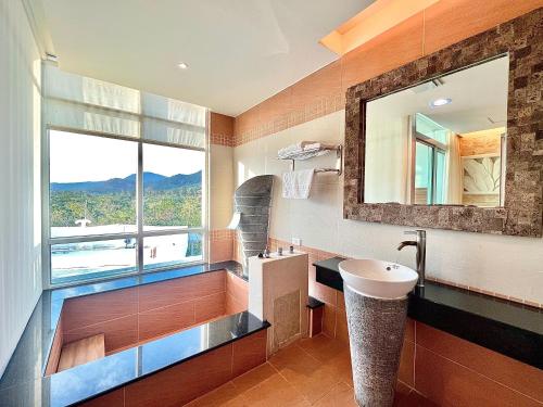 a bathroom with a sink and a mirror and a window at Seasons Bali Fashion Inn in Kenting