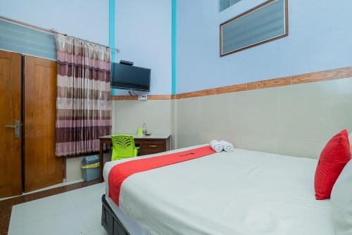 a bedroom with a bed and a desk and a television at RedDoorz Syariah near Alun-Alun Bojonegoro in Bojonegoro